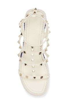 The fashion house's signature Rockstuds spike a resort-ready sandal boasting a caged silhouette and rope-wrapped wedge for a nautical lift. 3 3/4" (95mm) heel; 1 1/4" platform (size 9) 3" strap height Adjustable ankle strap with buckle closure Leather upper and lining/textile and synthetic sole Made in Spain Designer Shoes Designer Spiked Heels For Summer, Summer Wedge Sandals With Spikes, Designer Spiked Sandals For Summer, Summer Wedge Heel Sandals With Spikes, Luxury Spiked Sandals For Summer, Luxury White Heels For Beach, Luxury White Beach Heels, Luxury White Wedge Sandals For Summer, Rope Wrapped