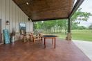 an outdoor covered porch with chairs and tables