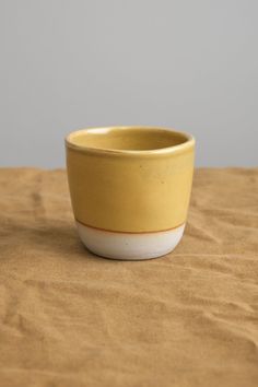 a yellow and white bowl sitting on top of a wooden table