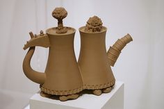 two clay vases sitting on top of a white block