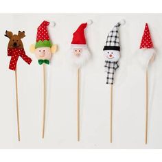 four christmas themed toothpicks with santa, snowman and reindeer heads on them