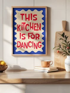 this kitchen is for dancing poster hangs on the wall next to a bowl of fruit