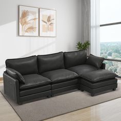 a living room with a black leather couch and ottoman in front of a large window