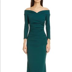 a woman in a long green dress with off the shoulder sleeves and an asymmetrical neckline