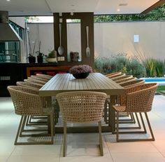 a dining room table with chairs and a bowl of flowers on it in front of a pool