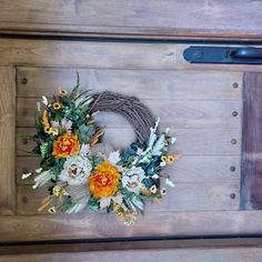 a wreath with flowers is hanging on the side of a wooden wall next to a pair of scissors