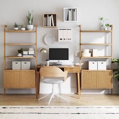 a desk with a computer on top of it in front of a wall mounted bookcase