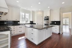 a large kitchen with white cabinets and black counter tops