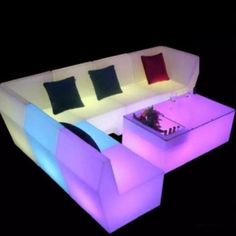 an illuminated couch and table with pillows on it