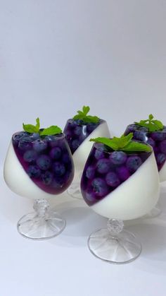 three glasses filled with blueberries and green leaves