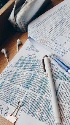 an open book and pen on top of paper with earbuds next to it