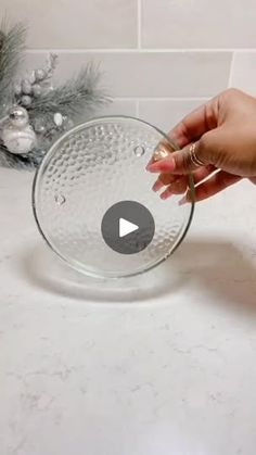 a person is holding a glass bowl in front of a christmas decoration on the counter