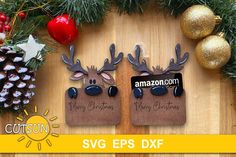 two reindeer magnets with christmas decorations and pine cones in the background on a wooden table