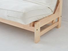 a wooden bed frame with white sheets and pillows on it's headrests