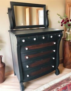 a black dresser with an ornate mirror on top