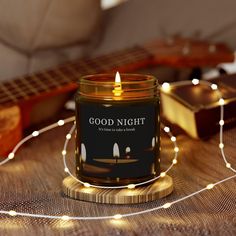 a candle sitting on top of a wooden table next to a guitar and string lights