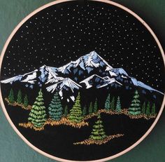 a hand embroidered mountain scene with pine trees and stars in the sky on a black background