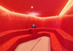 a room with red walls and flooring that is lit up by light from the ceiling