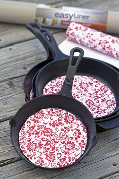 three red and white patterned pans sitting on top of a wooden table