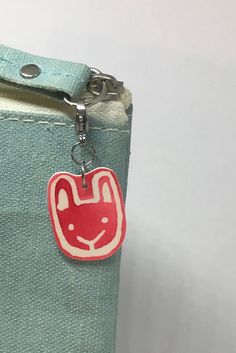 a small bag with a red and white face on the front hanging from a metal hook