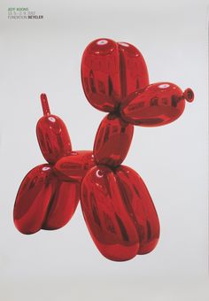 a red balloon dog is floating in the air