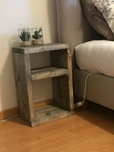 a small wooden shelf next to a bed