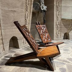 a wooden chair sitting on top of a stone floor next to a statue in the background