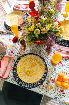 the table is set with colorful plates and flowers