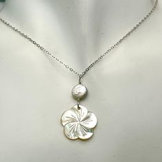 These lustrous mother of pearl flowers also have beautiful iridescence that is difficult to photograph. I paired them with a freshwater coin pearl that also have beautiful luster and iridescence. The mother of pearl flower is about 3/4 inch (19 mm) in width and has a beautiful freshwater coin pearl wrapped in a sterling silver wire wrap. The pendant is on delicate sterling silver chain and closes with a sterling silver spring clasp. This would be a beautiful accent for a beach wedding or to dres White Flower-shaped Mother Of Pearl Necklace, Silver Mother Of Pearl Shell Necklace, Silver Mother Of Pearl Round Shell Necklace, Silver Round Mother Of Pearl Shell Necklace, Gift Necklaces With High Luster Mother Of Pearl, Flower-shaped Mother Of Pearl Jewelry With Pearl Drop, Flower Shaped Mother Of Pearl Jewelry With Pearl Drop, Handmade Mother Of Pearl Flower Necklace, Pearl Jewelry With Mother Of Pearl Buttons For Gift