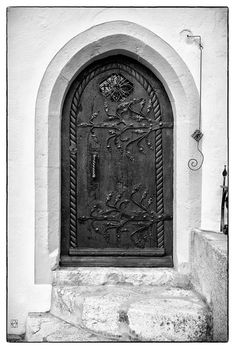 a black and white photo of a door with an arch in the wall next to it