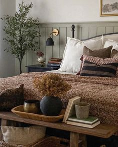 a bed sitting next to a table with books on top of it and two vases filled with flowers