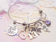 a silver bracelet with charms on it and the number thirteen is surrounded by confetti