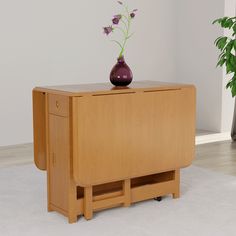 a wooden table with a vase on top of it next to a potted plant