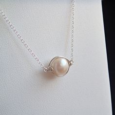 Caged Pearl Necklace- A single large pearl is wrapped in argentium sterling silver and suspended from sterling silver chain. Simple and elegant, this necklace is a unique take on classic pearls. The hand wired frame gives it a slightly organic feel and highlights the pearl wonderfully. Perfect whether for a special occasion or for wearing every day. Necklace is approximately 16 inches (40.6 cm) around, and the pearl itself is about 9 mm across. See some great coordinating earrings here: http://w Caged Pearl Necklace, Wire Wrapped Pearl Pendant, Royalcore Accessories, Adjustable Silver Wire-wrapped Pearl Necklace, Adjustable Silver Wire Wrapped Pearl Necklace, Elegant Silver Wire-wrapped Pearl Necklace, Elegant Silver Wire Wrapped Pearl Necklace, Silver Wire Wrapped Pearl Necklace Gift, Gift Silver Wire Wrapped Pearl Necklace