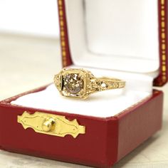 a fancy ring sits in a red box on the table next to it is a white and yellow diamond