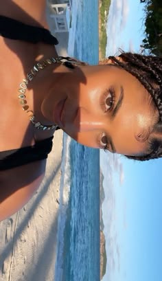 a woman with braids standing next to the ocean