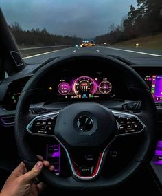 a person driving a car on a highway at night with the steering wheel illuminated up