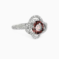 a white gold ring with an orange and pink diamond in the center, surrounded by diamonds