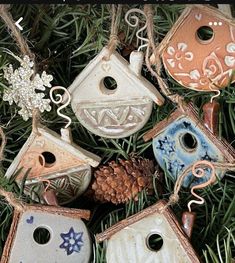 several bird houses hanging from a tree with pine cones and ornaments on it's branches