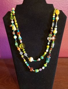 "This necklace is perfect for nature and wildlife lovers.  It features a tropical bird and has corresponding colors and is a wrap necklace that is 46\" in length.  It is bright and fun with yellows, greens, and blues.   Materials: wood, re-purposed beads,  polished stones, silver, plastic beads, glass beads  I began making jewelry in 2007 when I was living in Korea.  I was out shopping one day and found a carved jade piece that I fell in love with.  I thought it would look great on a necklace, s Living In Korea, Nature And Wildlife, Beading Crafts, Tropical Bird, Wrap Necklace, Carved Jade, Wrap Necklaces, Tropical Birds, Jade Carving