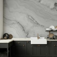 a kitchen with black cabinets and white marble counter tops, along with an open sink