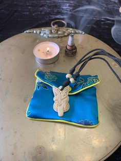 a small blue pouch sitting on top of a table next to a candle and some candles