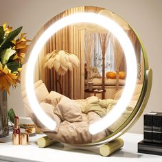 a round mirror sitting on top of a table next to a vase filled with flowers