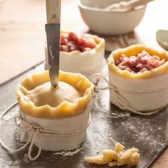 some food is being prepared and put in small containers with a knife on the table