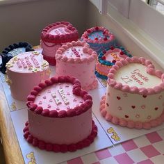 a table topped with lots of cakes on top of a checkerboard floor covered in pink frosting