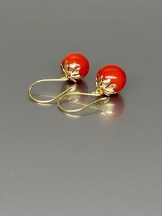 Gorgeous polished vibrant red coral globe earrings. The 12mm coral globes attached to beautiful 14K gold-filled flower caps as they dangle from the 14k gold-filled ear wires. The red globes are perfectly weighted while still being very comfortable to wear A truly gorgeous pair of earrings. *AAA coral spheres *Ball size (diameter): 12mm *Metal: 14K gold-filled *Earrings drop length: 31mm / 1.2 inch Solid gold, silver, and gemstones are also my materials of choice, I love working with these beauti Elegant Coral Colored Red Coral Earrings, Elegant Red Coral Drop Earrings, Elegant Red Coral Dangle Earrings, Elegant Red Coral Jewelry With Matching Earrings, Elegant Red Coral Earrings, Globe Earrings, Sphere Earrings, Red Stone Earrings, Ball Earrings