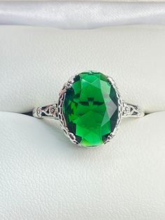 6ct. Simulated Emerald 925 Sterling Silver RingEdward Design#D70 This filigree ring is a reproduction of a sterling silver Edwardian antique with a simulated green emerald gemstone solitaire. This full cut oval gem is 14mm x 10mm. This ring sits 7mm off the finger. The inside of the band is marked 925 for sterling silver. Notice the beautiful leaf and floral design of the silver filigree setting and etched band. This ring is part of our Edward series, which includes bracelets, earring, and pendant necklaces. This is the original Edward design, with a generously cut gemstone that is accented above the filigree. This is a lovely rendition of an antique filigree ring. This amazing design is pure style and grace. You can dress it up or down, it's the perfect statement. Your every movement will Antique Green Emerald Ring With Prong Setting, Elegant Filigree Emerald Ring For Formal Occasions, Elegant Formal Emerald Ring With Filigree, Green Elegant Filigree Ring For Formal Occasions, Elegant Green Filigree Ring For Formal Occasions, Elegant Formal Emerald Filigree Ring, Green Elegant Formal Filigree Ring, Classic Sterling Silver Emerald Ring With Accent Stones, Classic Emerald Ring With Accent Stones In Sterling Silver