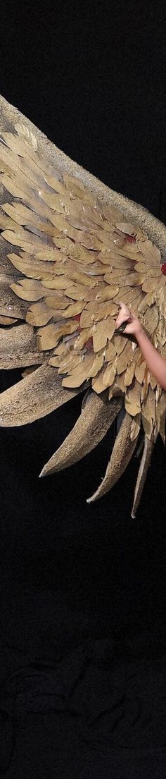 a woman is holding a large bird like object in her hand and it's wings spread out