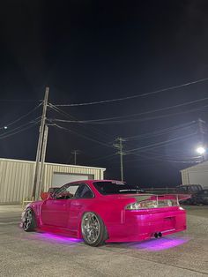 a pink car parked in a parking lot at night