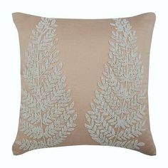 a beige pillow with white embroidered leaves on it